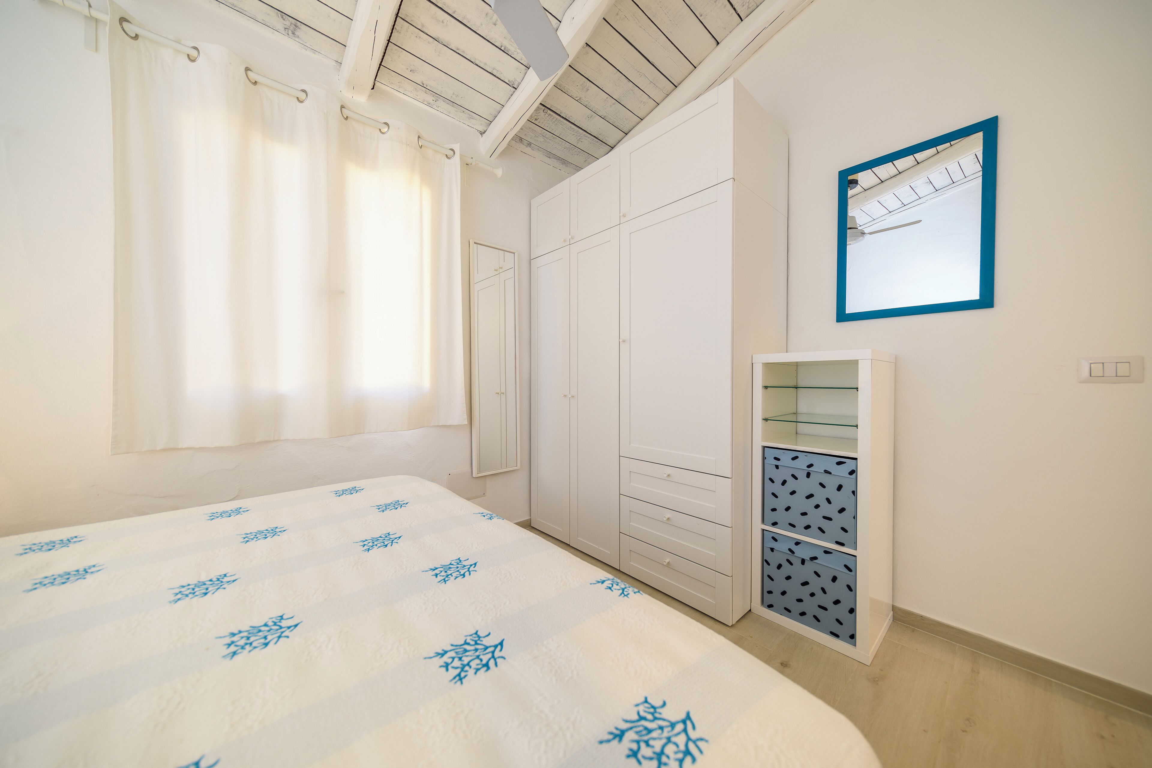 A bedroom with a bed, a wardrobe, and a mirror.