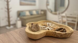 A wooden tray with seashells and driftwood on a table in a room with a mirror, a couch, and a painting on the wall. - Casetta in Calle (Chioggia)