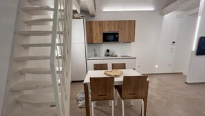 A modern kitchen with wooden cabinets, a microwave, and a dining area with two chairs and a table. - Casetta in Calle (Chioggia)