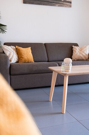 A modern living room with a grey sofa, a wooden coffee table, and decorative pillows. - Quiet loft studio - Pinel side (Saint-Martin)