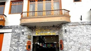 Un hotel con fachada de mármol, un letrero que dice 'Hotel Continental' y un balcón con barandilla de madera.