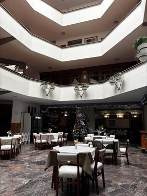 A multi-level dining area with tables and chairs, a Christmas tree, and a central staircase. - HOTEL CONTINENTAL (Cajamarca)