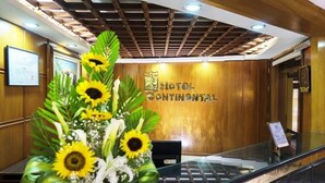 Un mostrador de recepción con una pared de madera y un cartel que dice 'HOTEL CONTINENTAL'.