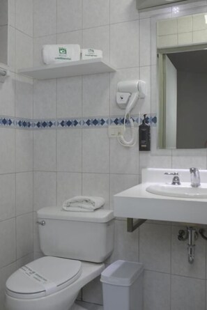 A bathroom with a toilet, sink, and a hairdryer on the wall. - HOTEL CONTINENTAL (Cajamarca)
