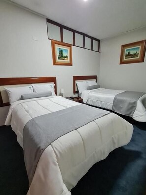 A hotel room with two beds, a nightstand, a lamp, and two framed pictures on the wall. - HOTEL CONTINENTAL (Cajamarca)