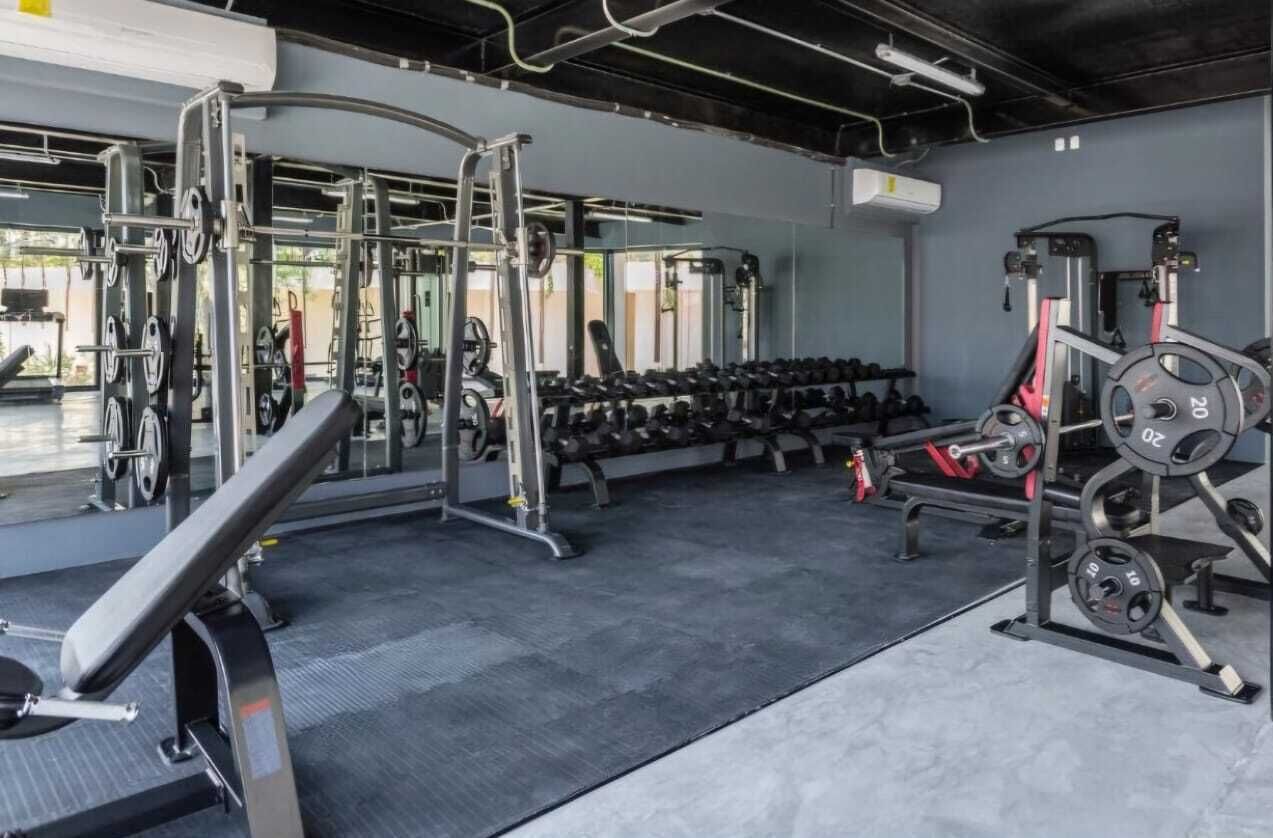 A gym with weightlifting equipment, dumbbells, and a bench.