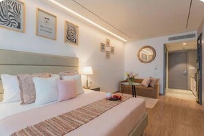 Ein Hotelzimmer mit einem Bett, einem Nachttisch, einer Lampe, einem Spiegel, einem kleinen Tisch mit einer Vase und einem Sofa.