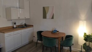 A compact kitchen with white cabinets, a wooden countertop, and a dining area with a round table and two chairs. - Authentic Stay in Little Havana  6 (Miami)