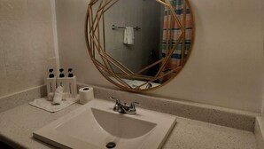 A bathroom with a round mirror, a sink, and toiletries. - Authentic Stay in Little Havana  6 (Miami)