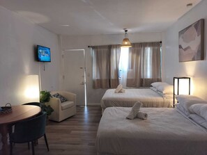 A hotel room with two beds, a TV, a desk, and a chair. - Authentic Stay in Little Havana  6 (Miami)
