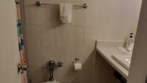 A small bathroom with a toilet, a towel rack, a sink, and a shower curtain. - Authentic Stay in Little Havana  6 (Miami)