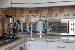 A kitchen with a coffee maker, toaster, kettle, and a microwave. - Comfy 3-Bed Family Flat in the Heart of Notting Hill (London)