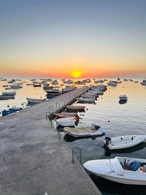 A pier with boats docked, leading to calm water with a sunset in the background. - Modern & Bright Maisonette • Private Terrace • Close to the Sea and Centre (Wied il-Għajn)