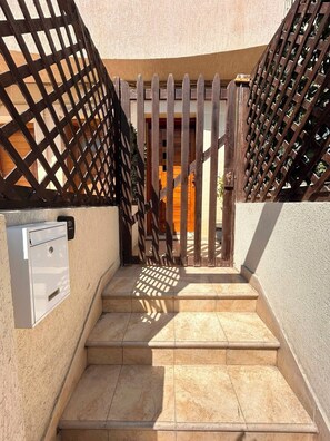 A set of outdoor stairs leading to a wooden gate with a metal box on the left. - Modern & Bright Maisonette • Private Terrace • Close to the Sea (Wied il-Għajn)
