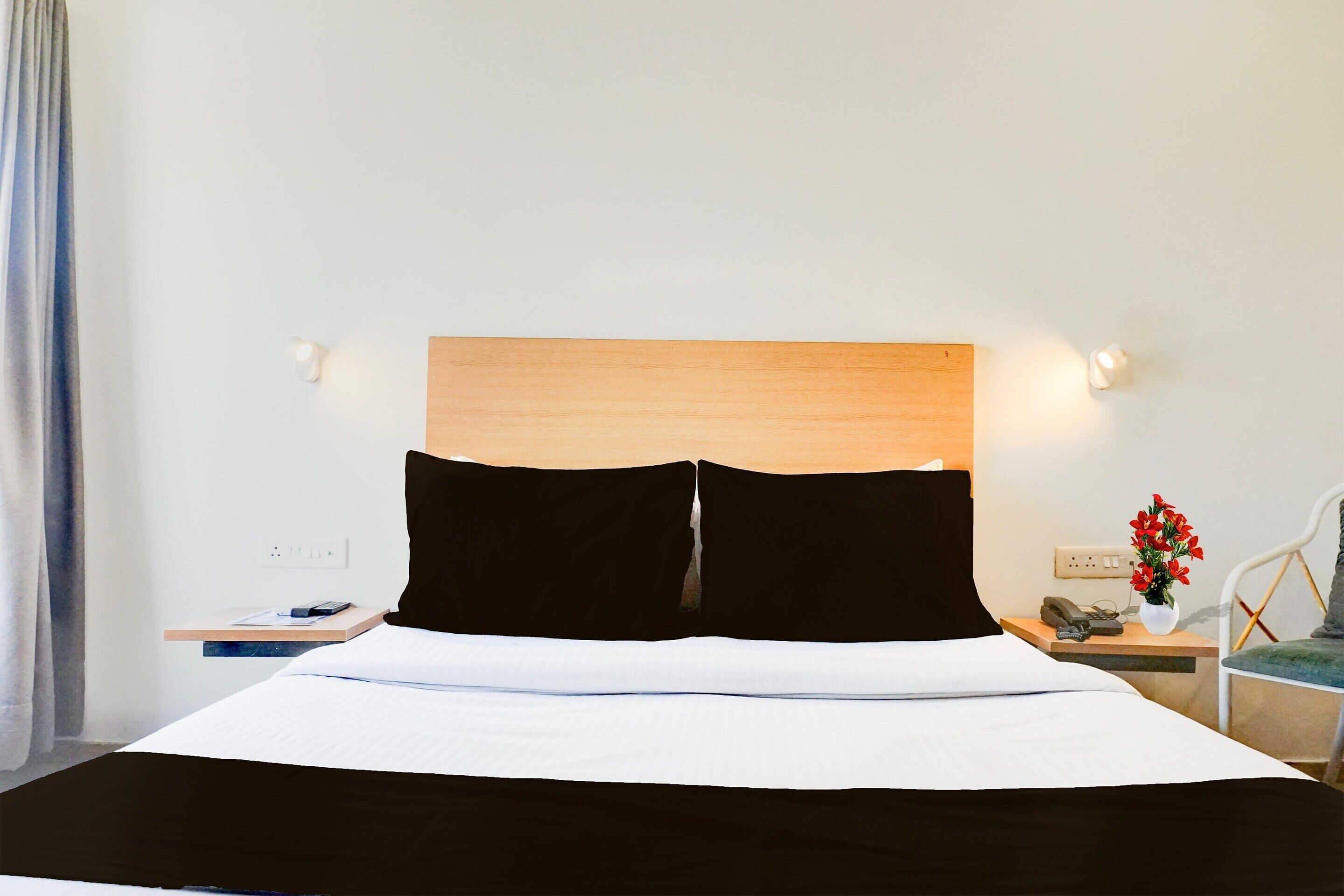 Ein Hotelzimmer mit einem Bett, Nachttischen, einer Lampe und einer Vase mit Blumen.