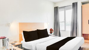 A hotel room with a bed, bedside table, and a window with curtains. - Classic With Balcony Hotel Town Plaza (Pune)