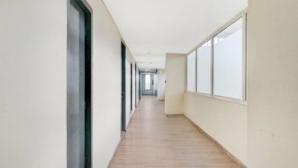 A long, narrow hallway with wooden flooring and large windows on one side. - Classic With Balcony Hotel Town Plaza (Pune)