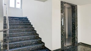 A staircase with a metal handrail leading to an elevator. - Classic With Balcony Hotel Town Plaza (Pune)