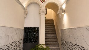 Un magnifique escalier, agrémenté de détails ornementaux au plafond et d’un blason.