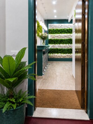Ein Flur mit grüner Wand, einem Blumentopf, einer Tür und einer Wandpflanzenwand.