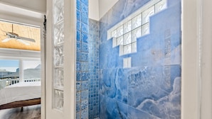 A bathroom with blue marble tiles, a shower area, and a window with a view of buildings. - 🏝️Private Pool + Game Room | Sleeps 15 | Steps to Beach | OWB Beach House (Pensacola Beach)