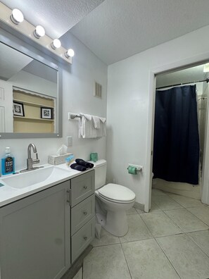 A bathroom with a sink, mirror, toilet, and shower curtain. - The Summit Next to Toostie’s – Beachfront Bliss! (Panama City Beach)