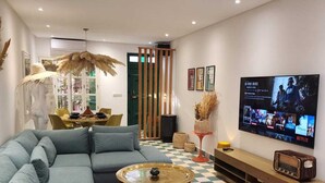 A modern living room with a sectional sofa, a coffee table, a TV, and a wicker chair. - DAR CACTUS-Private House Design-Rooftop-SPA (Marrakech)