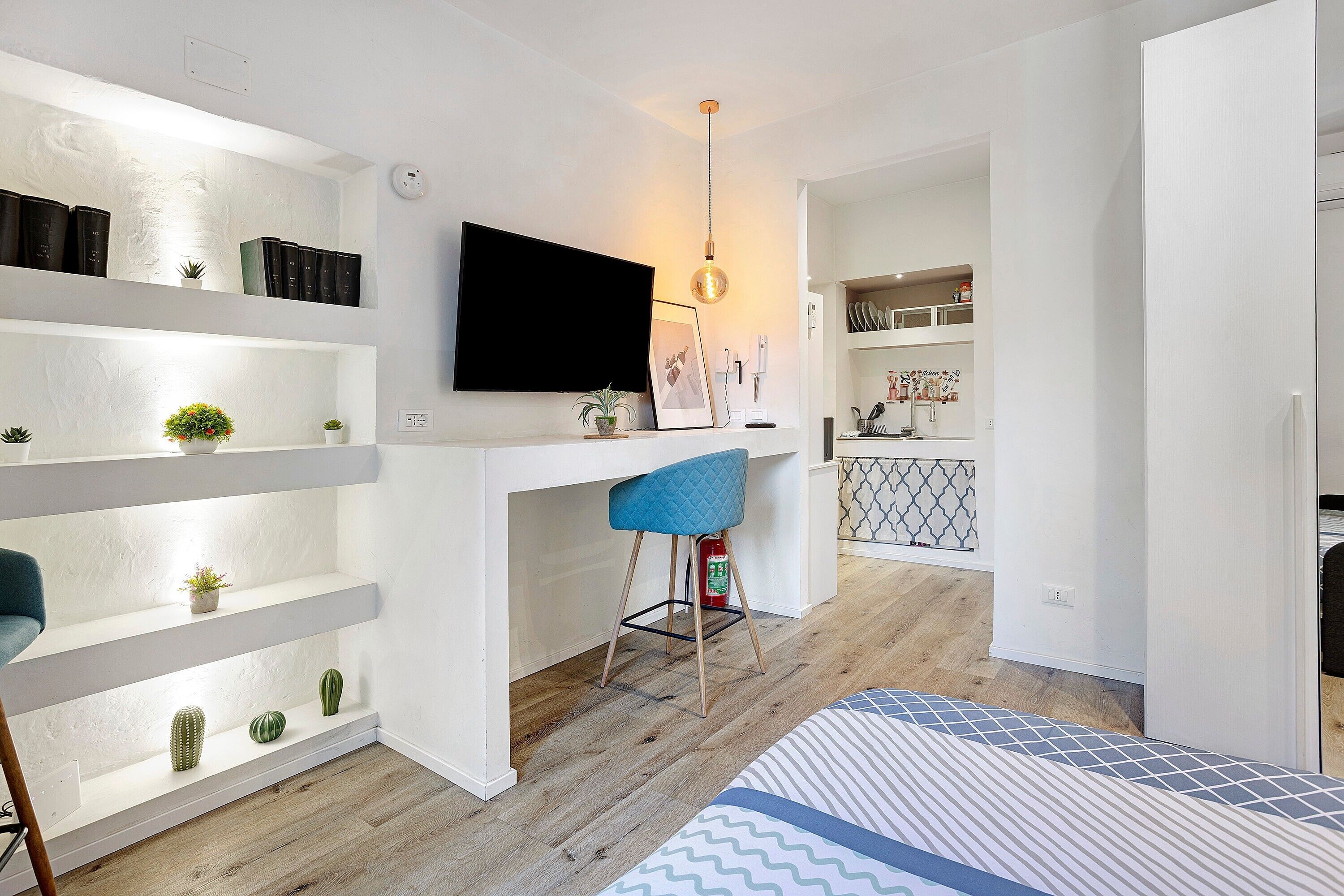 A modern living space with a kitchen area, a dining table, and a TV mounted on the wall.