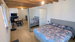 A bedroom with a bed, a desk, a chair, a TV, and a wardrobe.