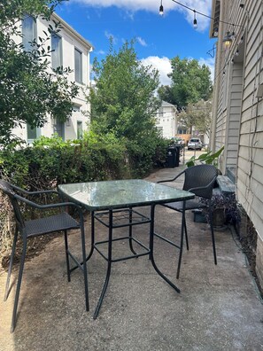 A patio with a glass table and chairs, surrounded by greenery and a building. - Relaxing 2-bedroom 2 bath Retreat in the Heart of New Orleans,  1700 Square Feet (New Orleans)