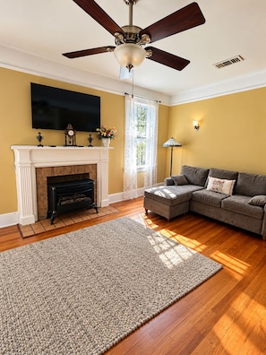 A living room with a fireplace, a sofa, a television mounted on the wall, and a ceiling fan. - Relaxing 2-bedroom 2 bath Retreat in the Heart of New Orleans,  1700 Square Feet (New Orleans)