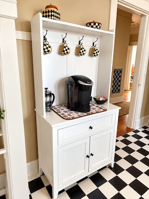 A kitchen area with a coffee maker on a countertop, a hanging rack with mugs, and a checkered floor. - Relaxing 2-bedroom 2 bath Retreat in the Heart of New Orleans,  1700 Square Feet (New Orleans)