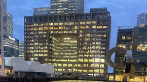 Blick auf das Wasser mit einem modernen Gebäude, das eine Fensterfront und eine Skulptur im Vordergrund zeigt.