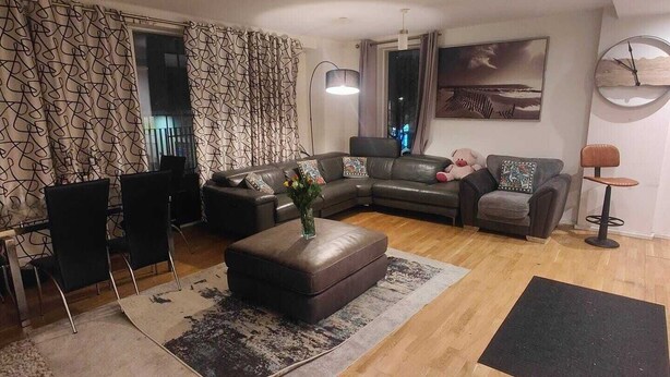 Ein modernes Wohnzimmer mit einem Ecksofa, einem Couchtisch und einem Essbereich mit Stühlen.