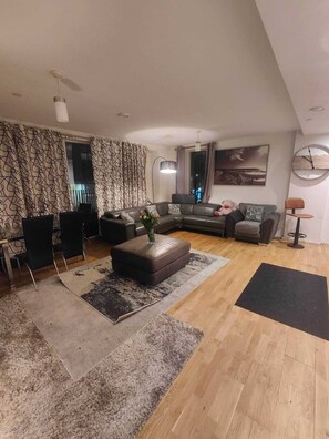 A modern living room with a sectional sofa, a coffee table, and a dining area with chairs.