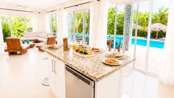 A modern kitchen with a central island, large windows, and a view of a swimming pool.