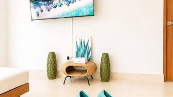 A living room with a television mounted on the wall displaying a beach scene, a chessboard, and two vases on a coffee table.