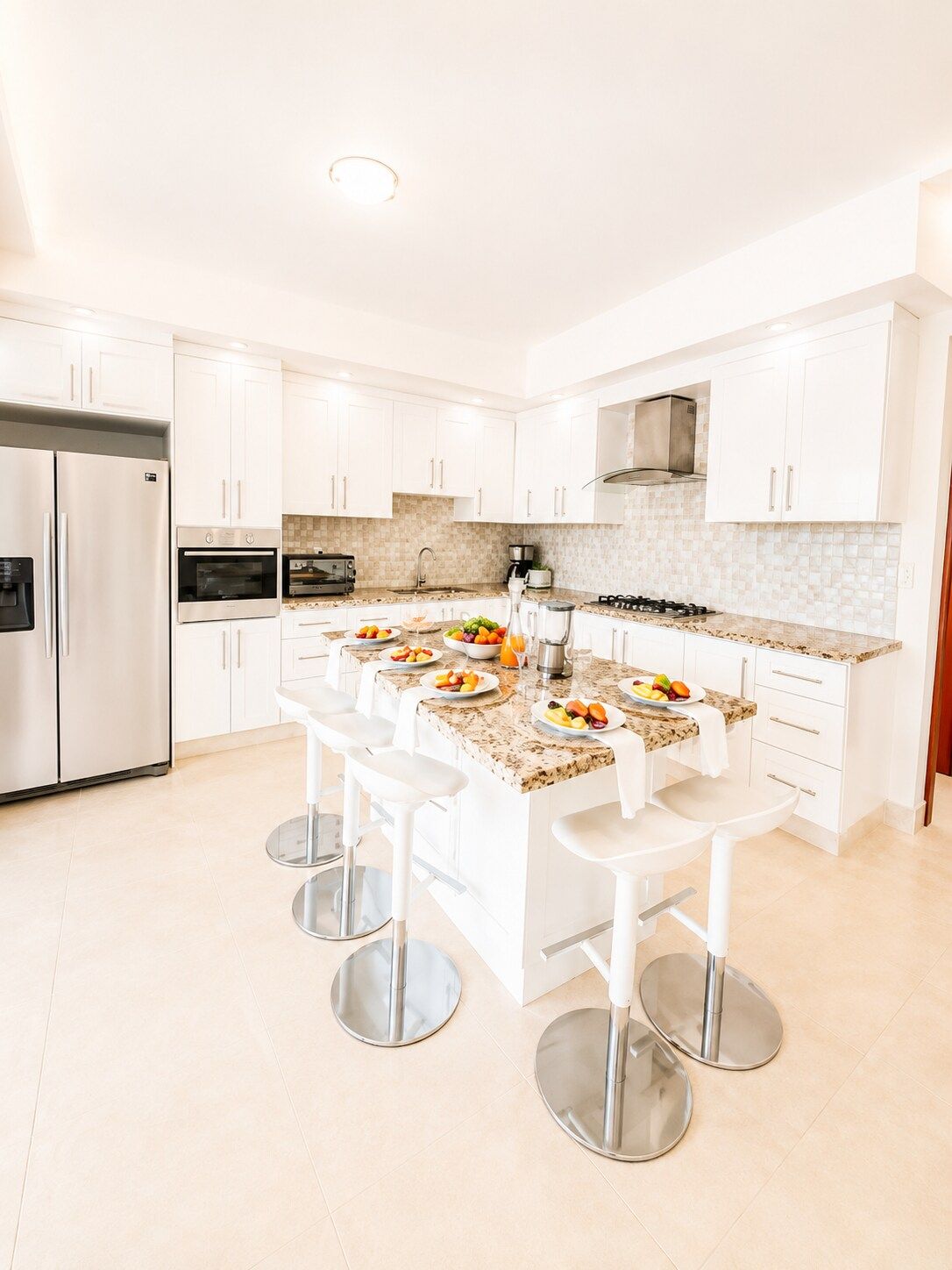 A modern kitchen with white cabinetry, stainless steel appliances, and a central island with bar stools.