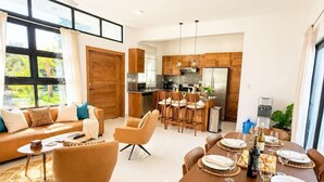 Ein modernes Wohnzimmer mit Sofa, Sesseln und einem Essbereich, gedeckt für eine Mahlzeit.