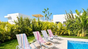 Ein Poolbereich mit Liegestühlen und einem Gebäude im Hintergrund.