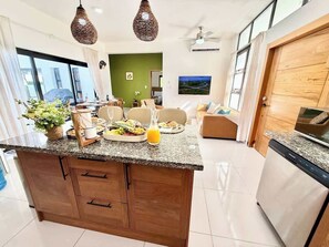 A modern kitchen with granite countertops, wooden cabinetry, and a built-in dishwasher. - 3bd Villa Aura in Oceanfront Comm Sosua Ocean Vill (Sosúa)
