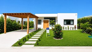 A modern two-story house with a covered patio, a well-maintained lawn, and a clear blue sky. - 3BD Villa in SOV | Private Pool & Peaceful Retreat (Sosúa)