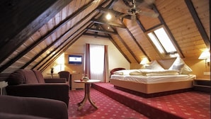 An attic bedroom with a bed, a small table, and a TV. - Gasthof Hirsch (Gengenbach)