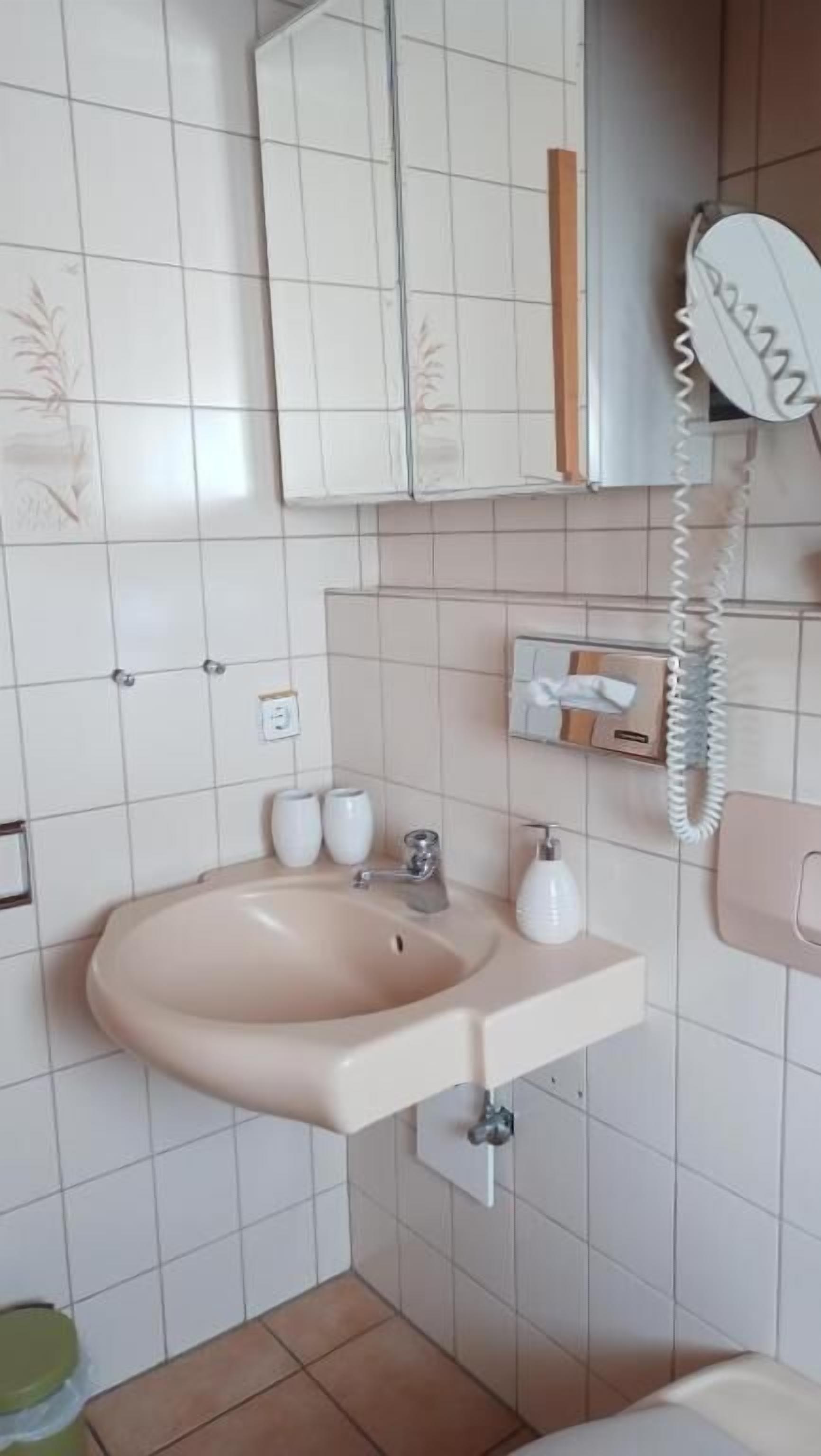 A bathroom with a sink, mirror, telephone, and toiletries.