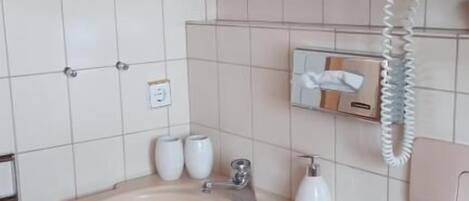 A bathroom with a sink, mirror, telephone, and toiletries.