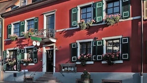 A red building with green shutters, a balcony, and flower boxes. - Gasthof Hirsch (Gengenbach)