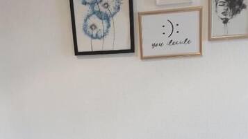 A small room with a wooden table, a single chair, and three framed artworks on the wall.