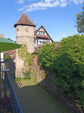 A historic stone tower and a traditional half-timbered building with a cobblestone pathway and greenery. - Gasthof Hirsch (Gengenbach)