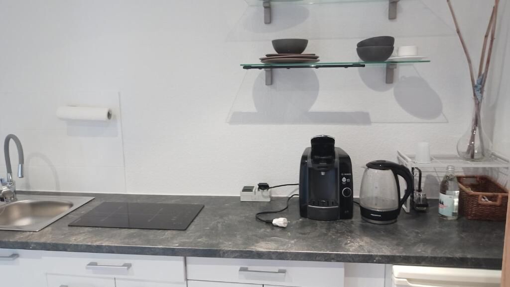 A kitchen with a coffee maker, kettle, and a basket.