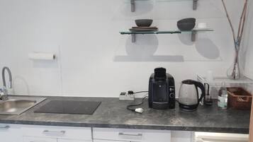 A kitchen with a coffee maker, kettle, and a basket.